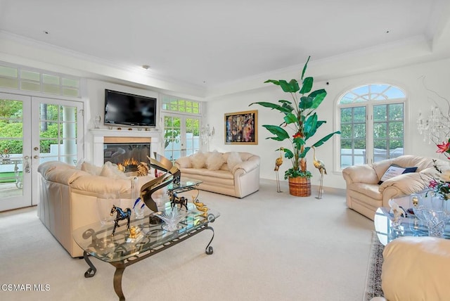 carpeted living room with french doors, crown molding, a raised ceiling, and a wealth of natural light