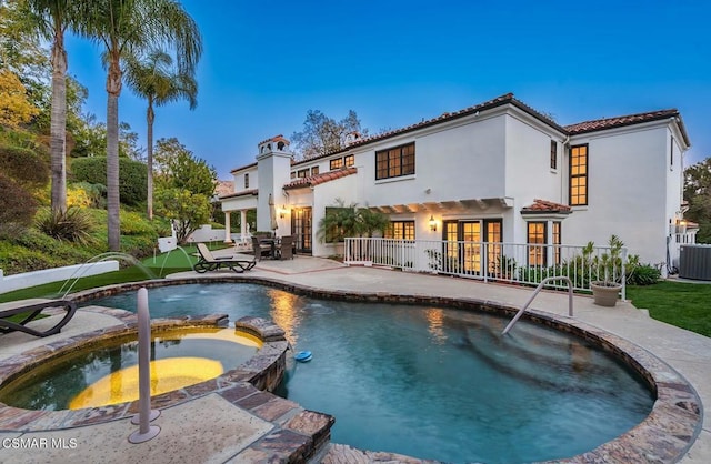 back of house with a pool with hot tub, central AC, and a patio