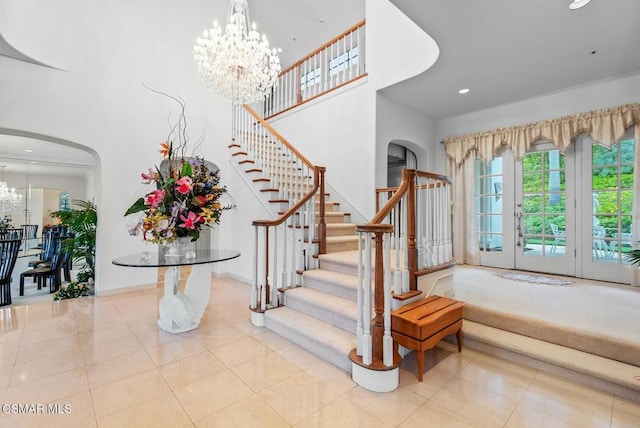 foyer entrance with light tile patterned flooring, a towering ceiling, and a notable chandelier