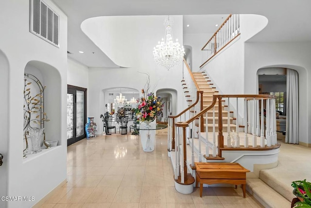 tiled entryway with an inviting chandelier and a towering ceiling