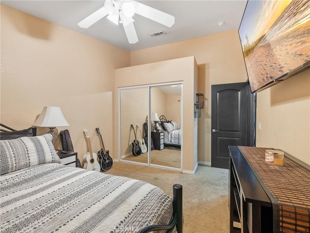 bedroom with ceiling fan, light carpet, and a closet