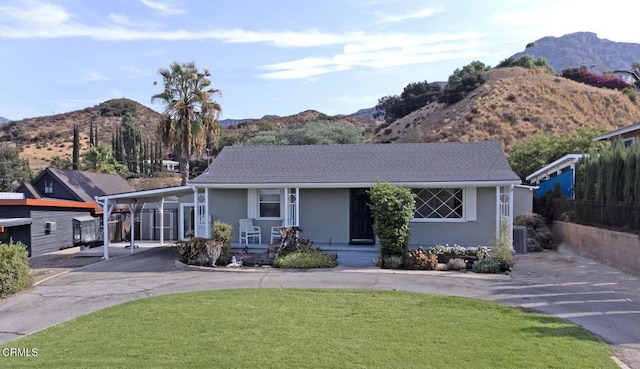 view of front of house with central AC unit, a carport, a mountain view, and a front lawn