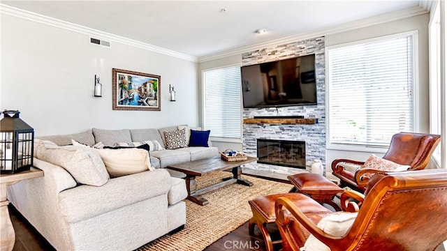 living room with crown molding, a stone fireplace, and hardwood / wood-style floors