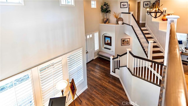 stairs with a chandelier, hardwood / wood-style floors, and a high ceiling