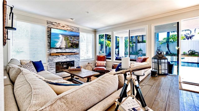 living room featuring crown molding, a stone fireplace, and hardwood / wood-style flooring