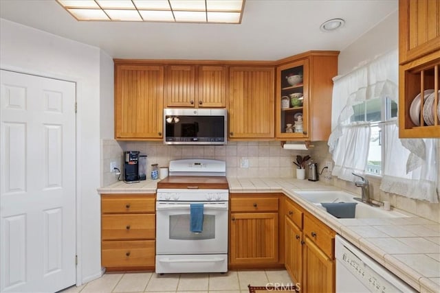 kitchen featuring sink, white appliances, tile countertops, and backsplash