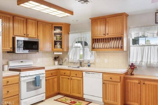 kitchen featuring tasteful backsplash, sink, tile countertops, and white appliances