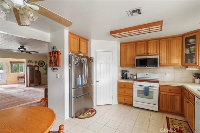 kitchen featuring backsplash, tile countertops, stainless steel appliances, and ceiling fan