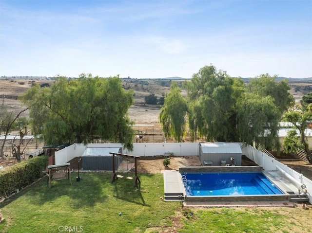 view of swimming pool with a rural view and a lawn