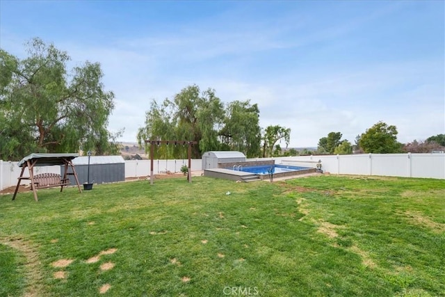 view of yard with a fenced in pool and a storage unit