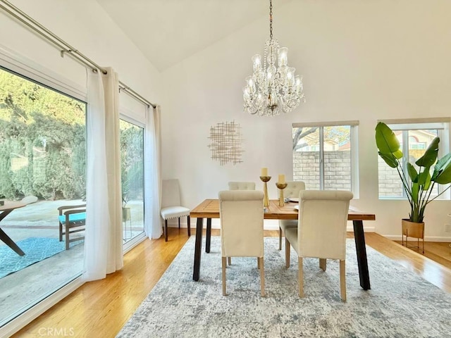 dining room with high vaulted ceiling, a chandelier, and light wood-type flooring