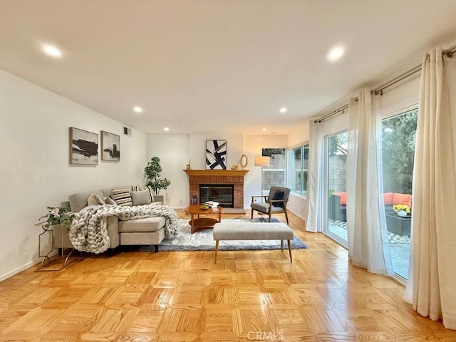 living room featuring a brick fireplace and light parquet floors