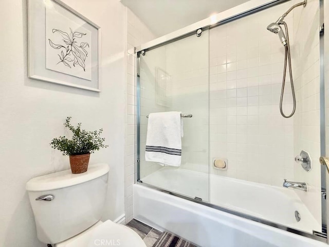 bathroom featuring bath / shower combo with glass door and toilet