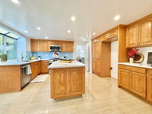 kitchen featuring stainless steel appliances, a kitchen island, sink, and backsplash