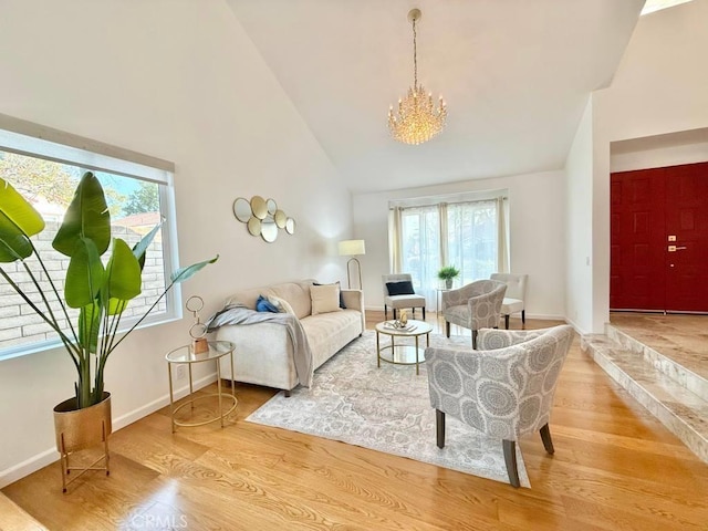 living room with an inviting chandelier, high vaulted ceiling, and light hardwood / wood-style floors