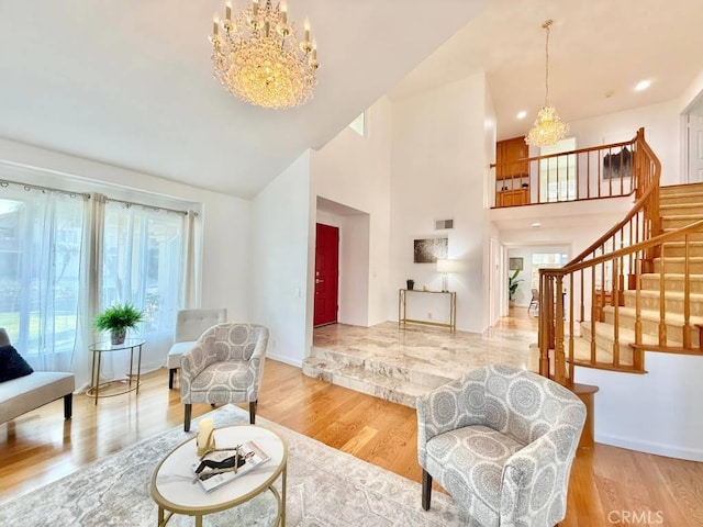 living room with high vaulted ceiling, light hardwood / wood-style floors, and a notable chandelier