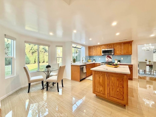 kitchen with a kitchen island, appliances with stainless steel finishes, sink, backsplash, and a chandelier