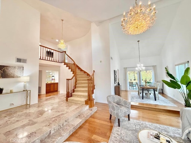 foyer entrance with high vaulted ceiling, light hardwood / wood-style flooring, and a notable chandelier