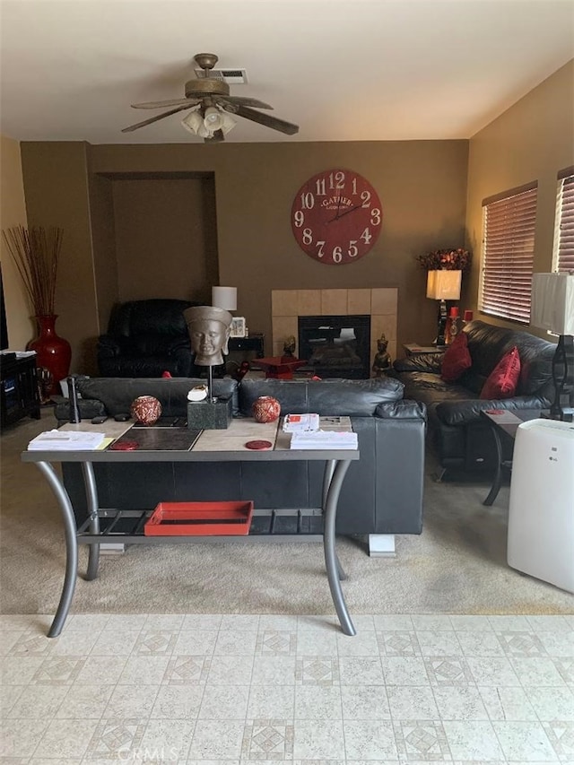 living room with ceiling fan and a tiled fireplace