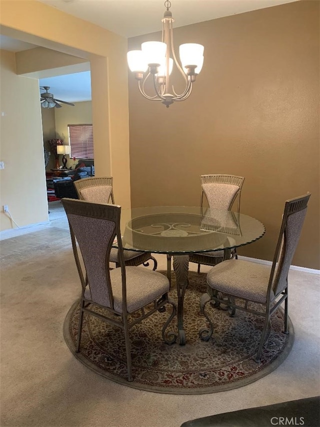 dining area featuring carpet and ceiling fan with notable chandelier