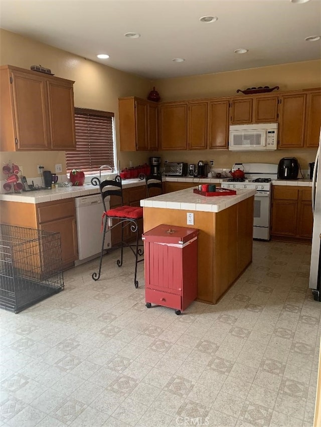 kitchen with sink, a center island, tile countertops, and white appliances