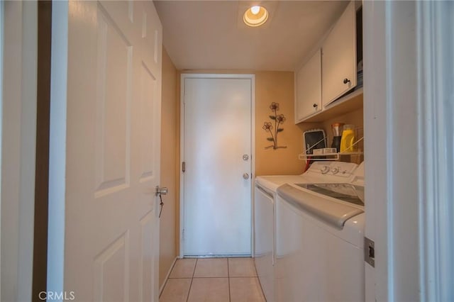 clothes washing area with independent washer and dryer, cabinets, and light tile patterned flooring