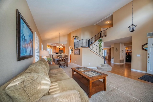 carpeted living room featuring high vaulted ceiling and a chandelier