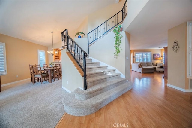 staircase with hardwood / wood-style flooring and a notable chandelier