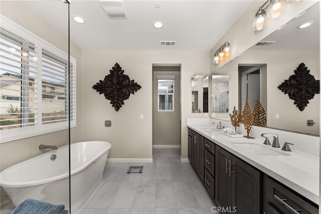 bathroom featuring a freestanding tub, a sink, and visible vents