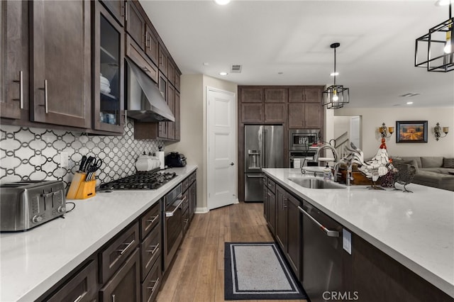 kitchen featuring dark brown cabinetry, stainless steel appliances, a sink, light countertops, and dark wood-style floors