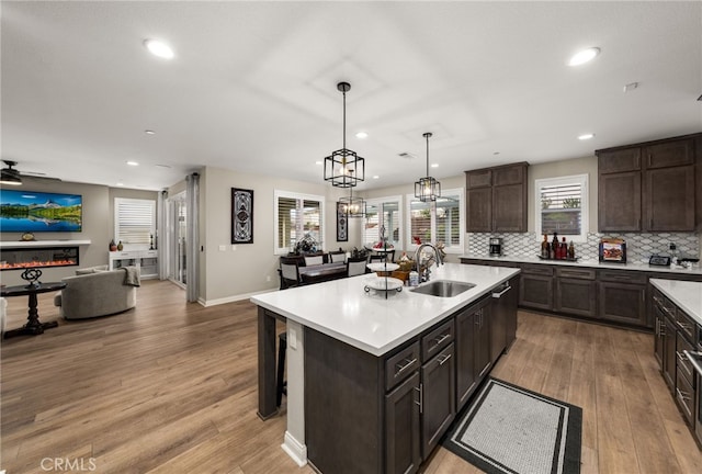 kitchen with light wood finished floors, light countertops, a glass covered fireplace, and a sink