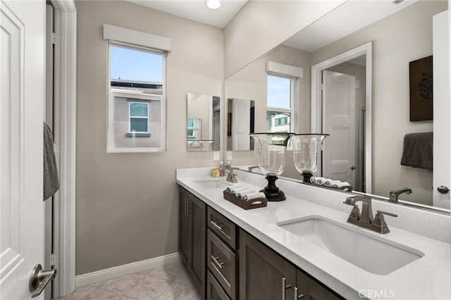 full bathroom with double vanity, baseboards, a sink, and tile patterned floors