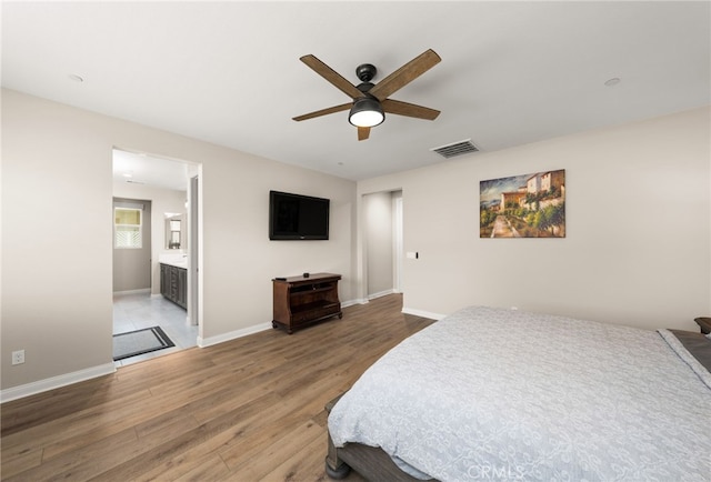 bedroom featuring baseboards, visible vents, ensuite bath, ceiling fan, and wood finished floors