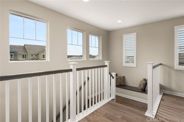 hallway with recessed lighting, baseboards, an upstairs landing, and wood finished floors