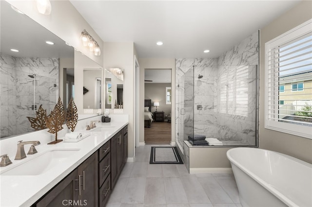 ensuite bathroom with double vanity, a freestanding tub, a marble finish shower, and a sink