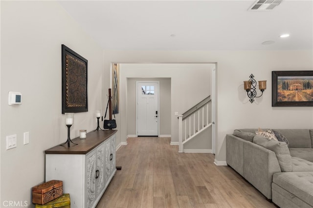 interior space with stairway, light wood-style flooring, visible vents, and baseboards