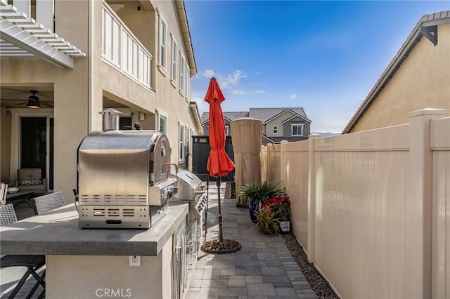 view of patio / terrace featuring ceiling fan, exterior kitchen, a fenced backyard, and outdoor wet bar