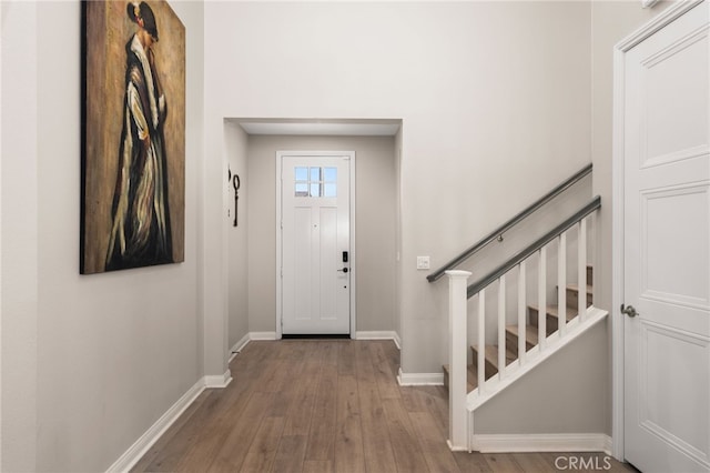 foyer entrance with stairs, baseboards, and wood finished floors