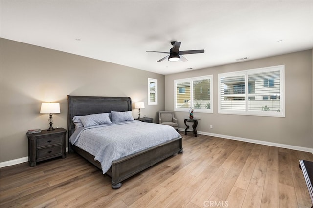 bedroom with light wood finished floors, a ceiling fan, visible vents, and baseboards