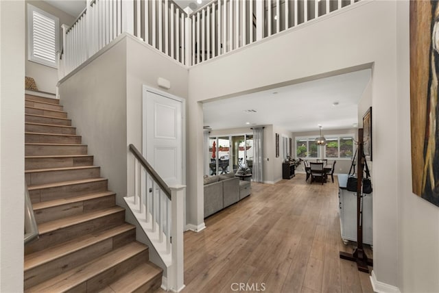 entryway featuring stairway, a towering ceiling, baseboards, and hardwood / wood-style flooring