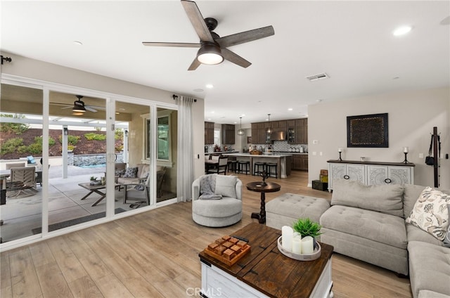 living area with light wood-style floors, visible vents, and recessed lighting