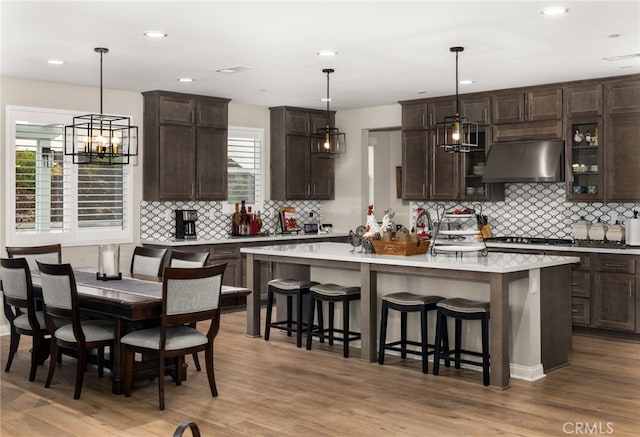 kitchen with under cabinet range hood, a breakfast bar area, light countertops, and dark brown cabinets