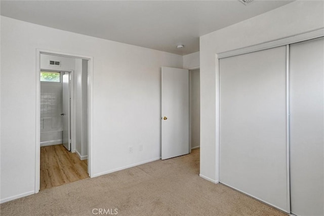 unfurnished bedroom with light colored carpet and a closet