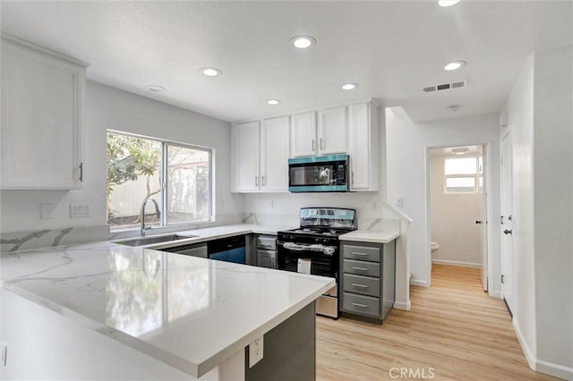 kitchen featuring sink, kitchen peninsula, a wealth of natural light, stainless steel appliances, and white cabinets