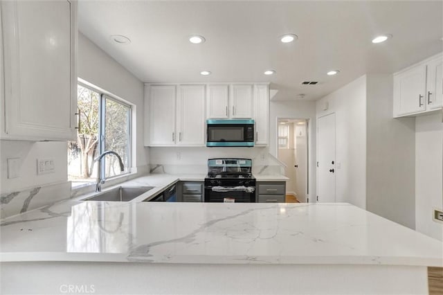 kitchen featuring sink, light stone counters, range, kitchen peninsula, and white cabinets