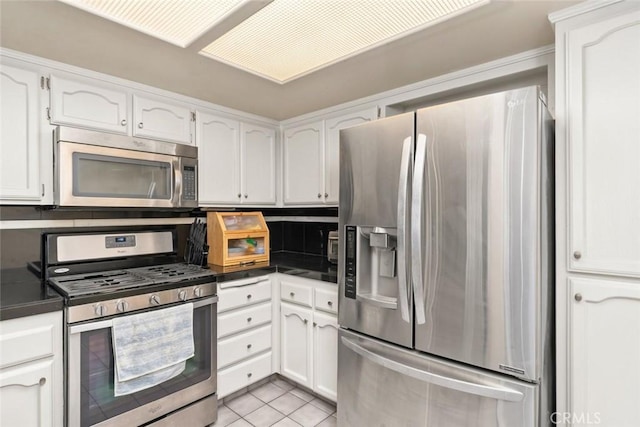 kitchen featuring tasteful backsplash, white cabinetry, appliances with stainless steel finishes, and light tile patterned floors