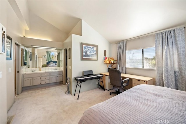 bedroom featuring lofted ceiling, sink, ensuite bath, and light carpet