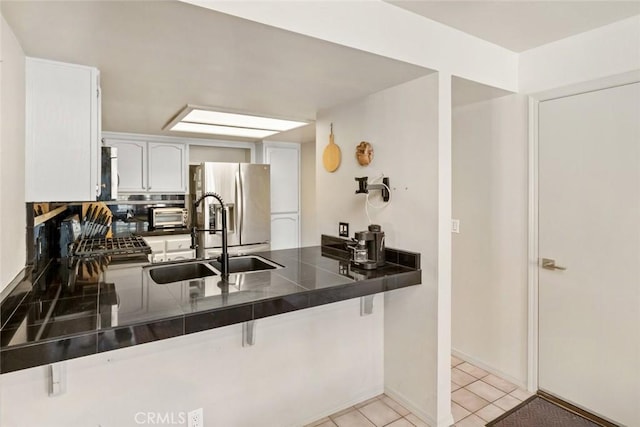 kitchen featuring stainless steel refrigerator with ice dispenser, sink, white cabinetry, range, and kitchen peninsula