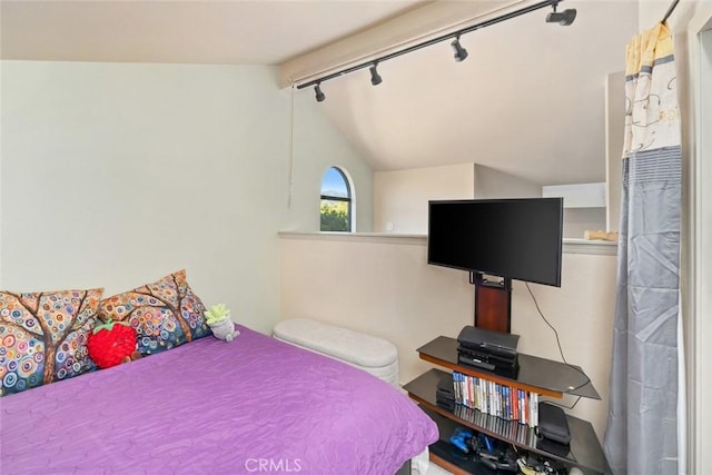 bedroom featuring rail lighting and lofted ceiling