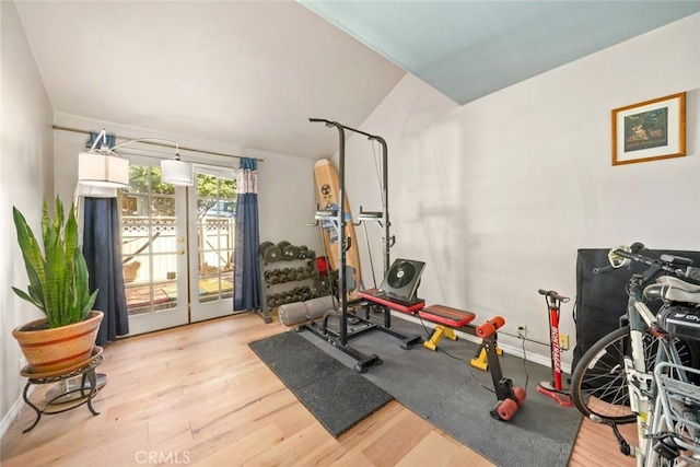 workout room with lofted ceiling, light hardwood / wood-style floors, and french doors